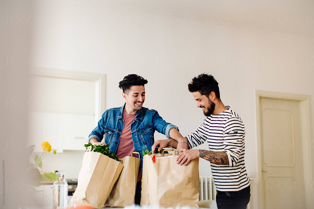 Ethnic gay couple unpacking groceries at home