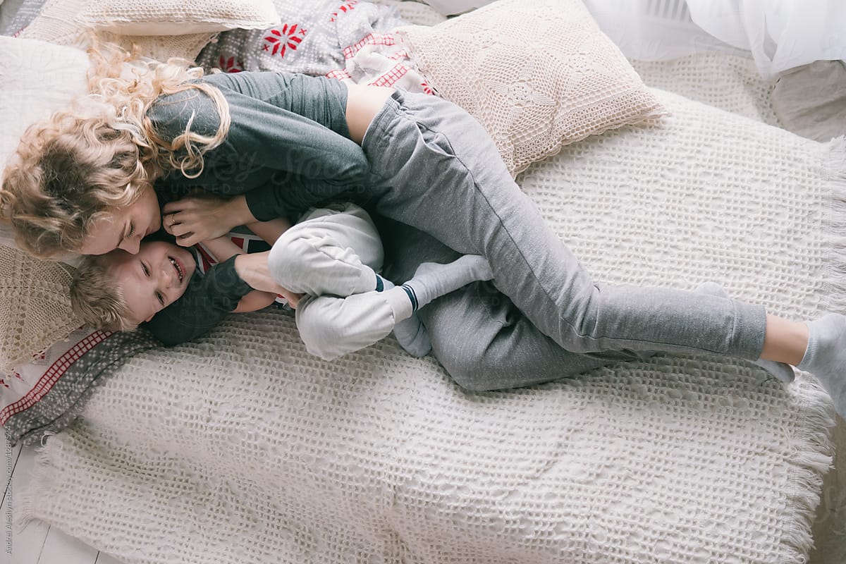 cute family mother and son laughing and playing in the morning bed