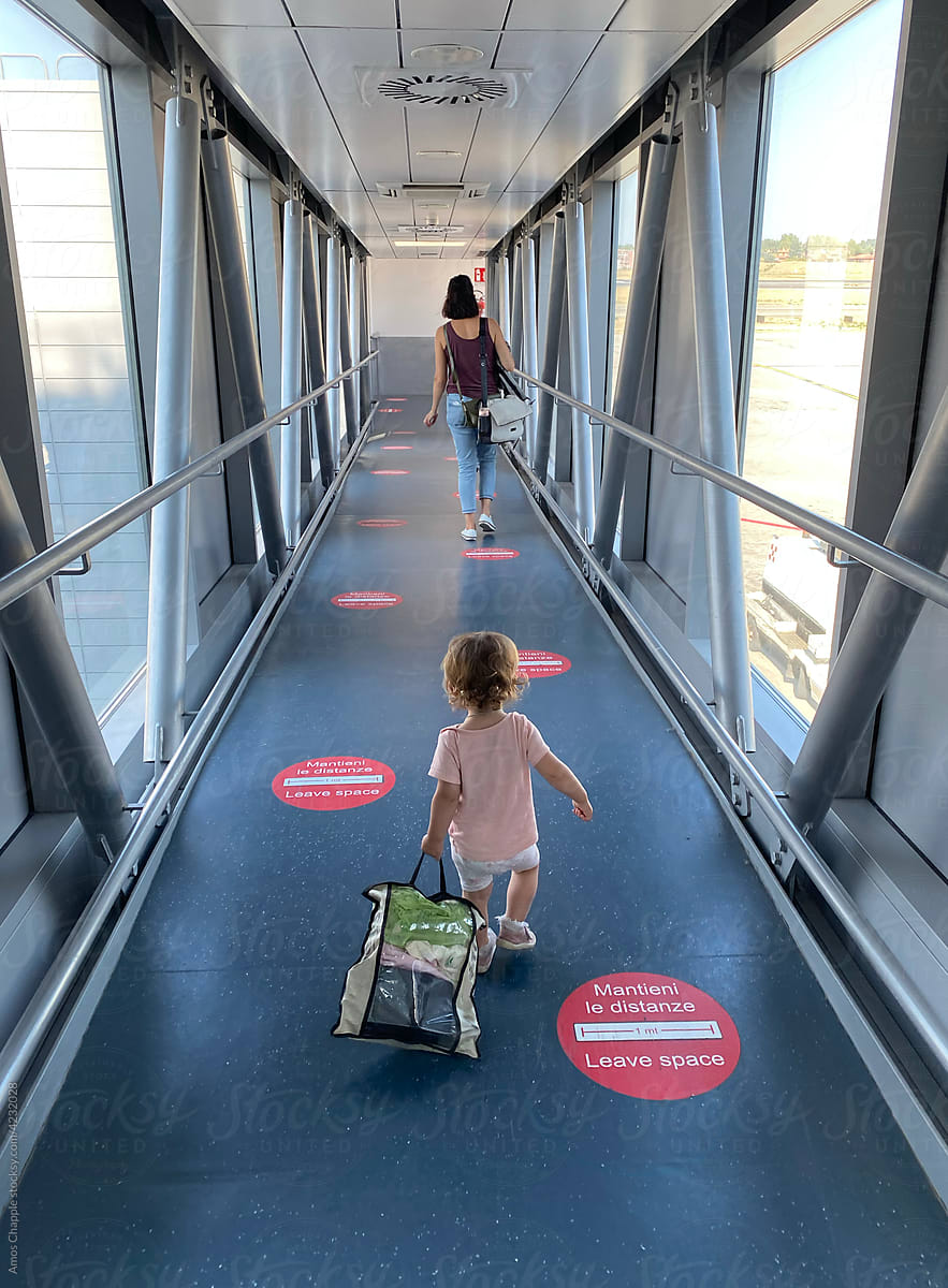 A little girl follows her mum through an airbridge.