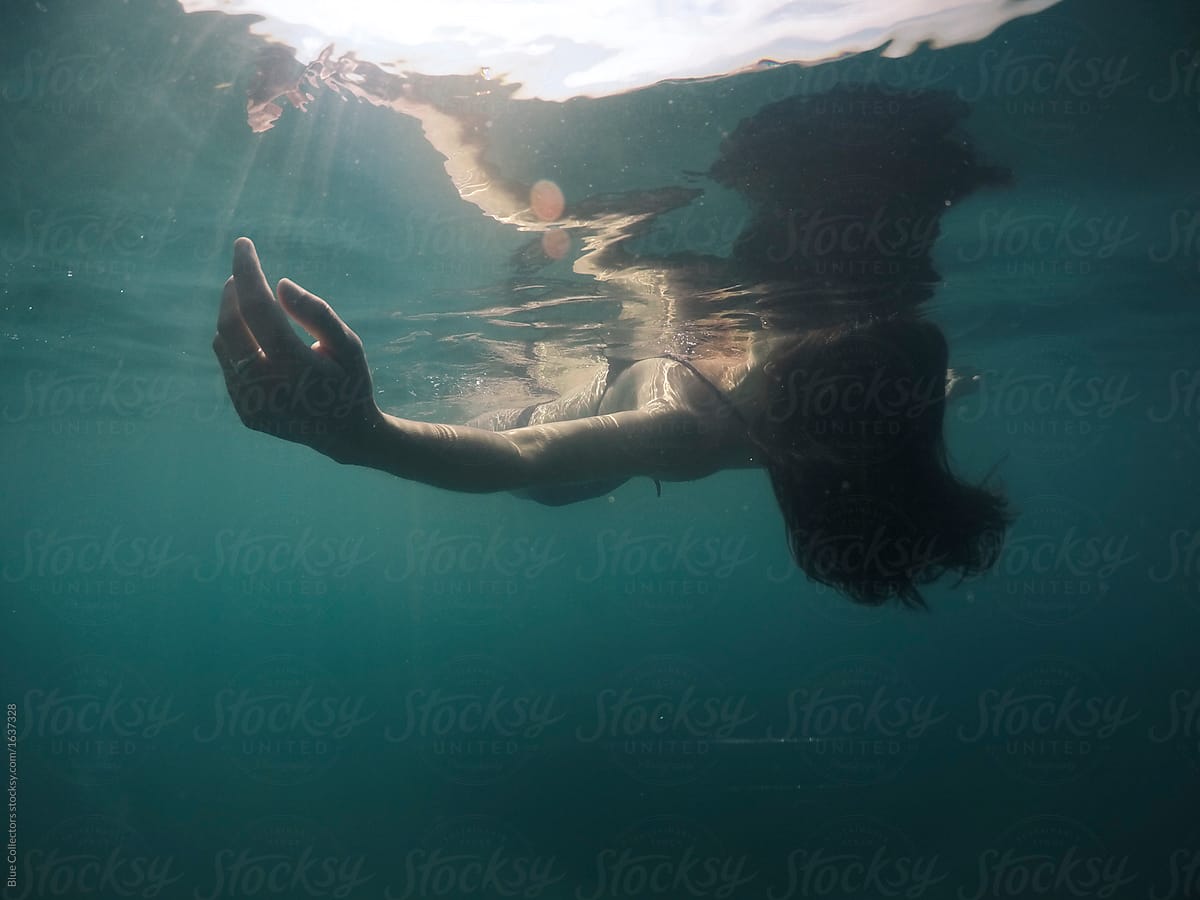 Peaceful Woman Floating In The Water From Underwater View Del Colaborador De Stocksy Blue