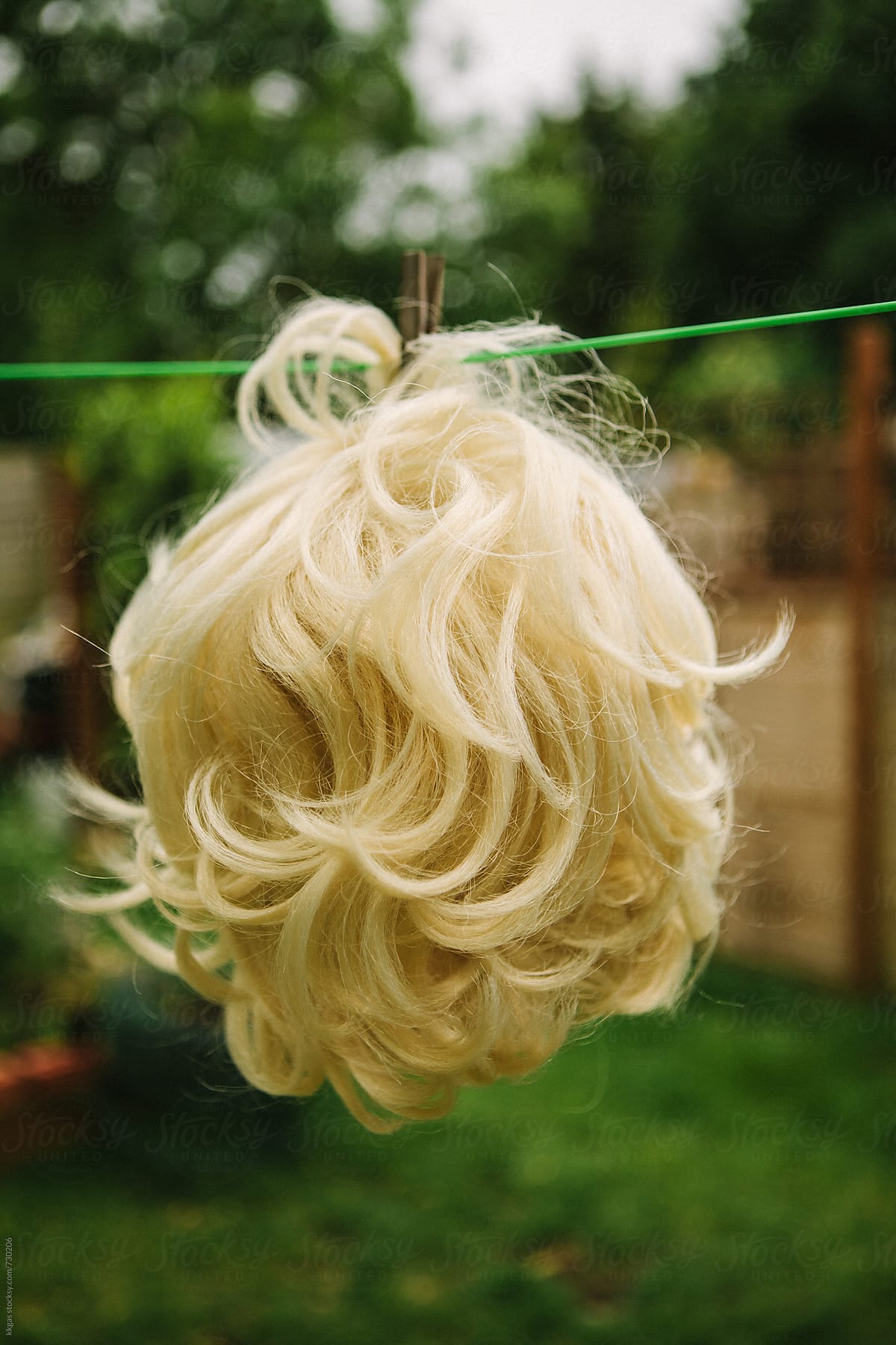 Blonde wig hanging on a washing line to dry