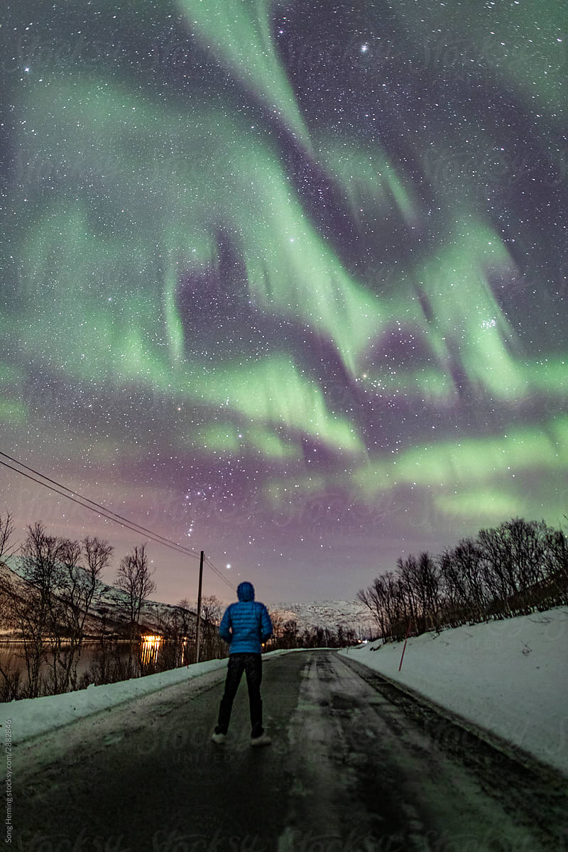 A male stand on the ice road with northern light aurora at night