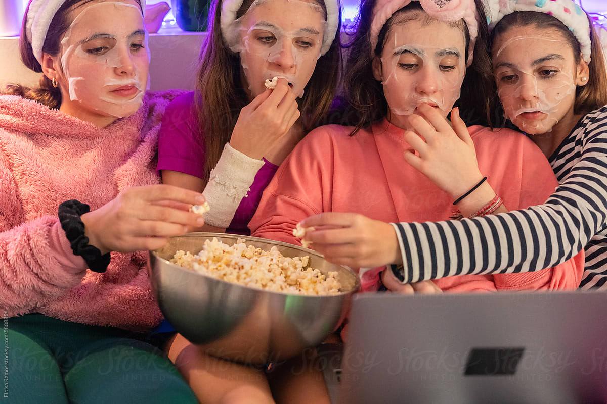 Young girls with facial mask watching movie in laptop
