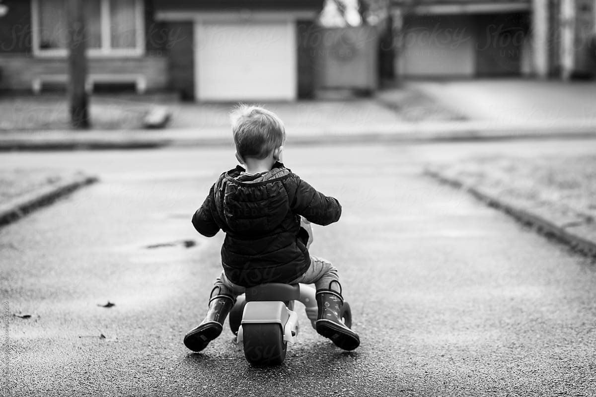 black and white image of a toddler on a tricycle