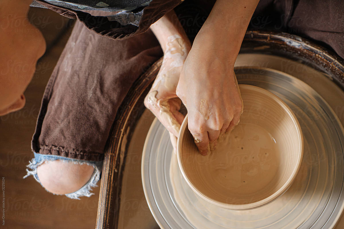 woman in torn jeans makes a plate on a potter's wheel