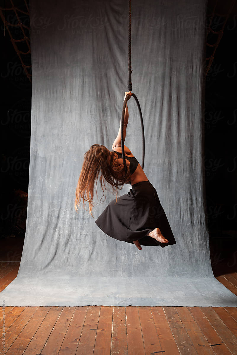 Aerial artist in a beautiful pose on a Lyra or Aerial hoop