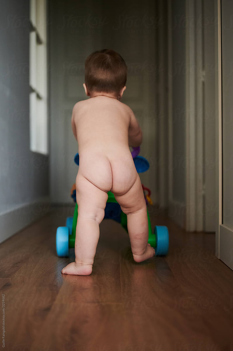 Naked baby doing first steps
