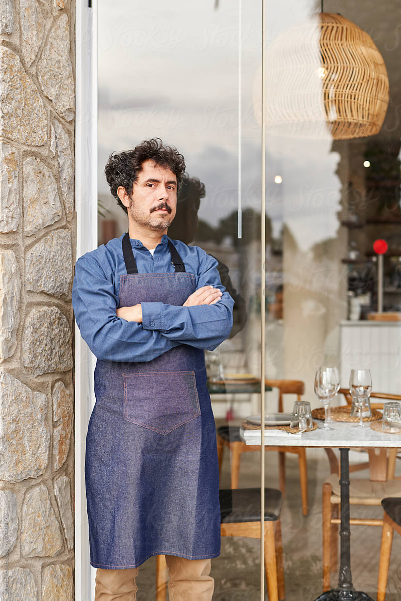 Restaurant owner in apron near glass wall