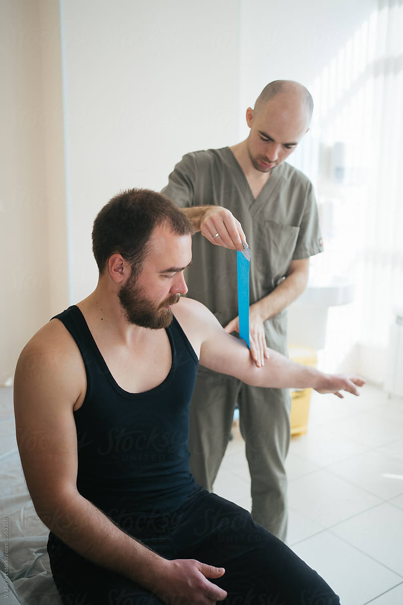 Doctor using kinesiotaping techniques on patient