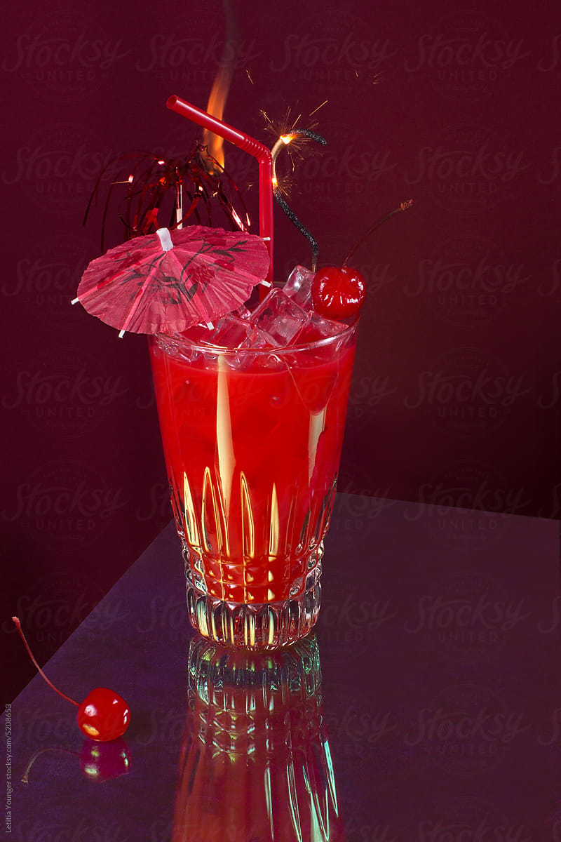 Red cocktail with red umbrella and cherries