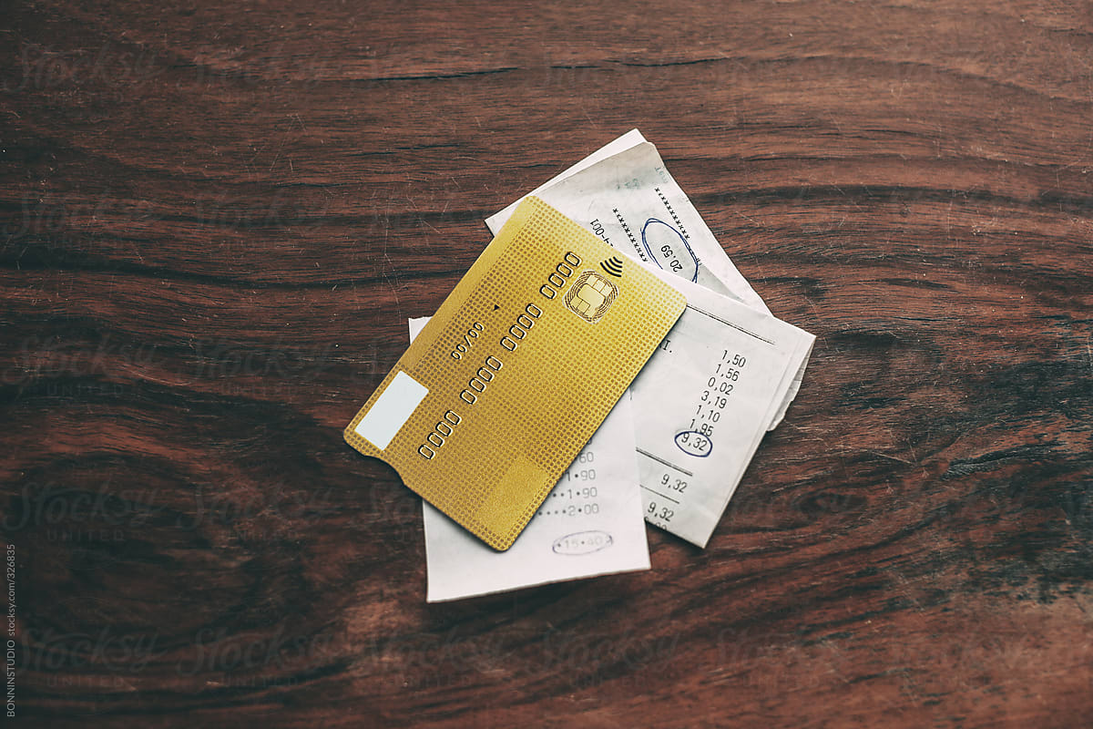 Gold credit card and some tickets on a wooden table.