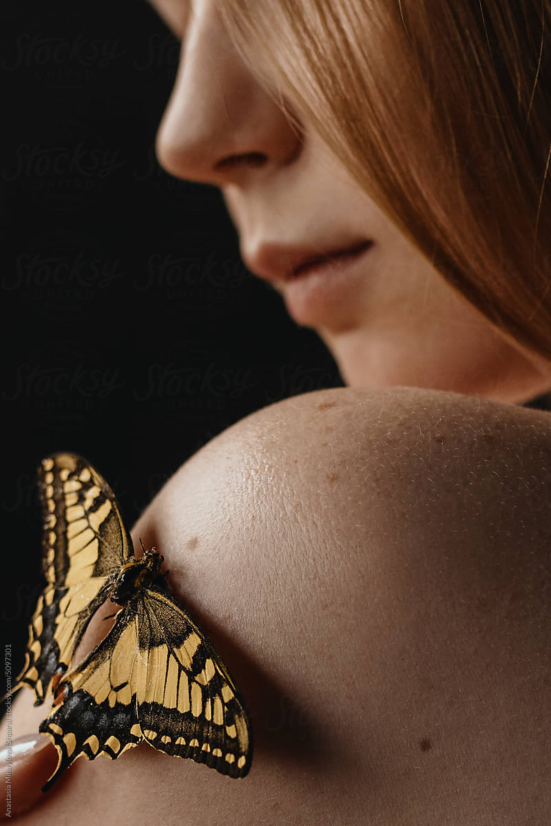 Close up photo of the skin texture of woman\'s shoulder and butterfly