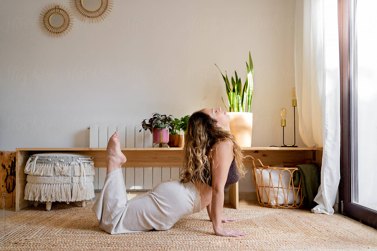 Fit woman practicing yoga at living room floor