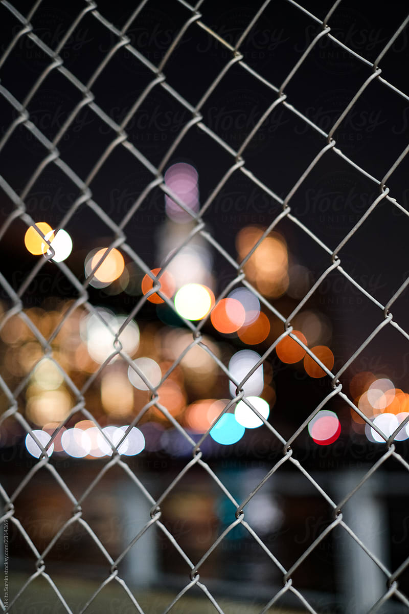 Photo of the night city through the iron fence. New York at night glows with lights