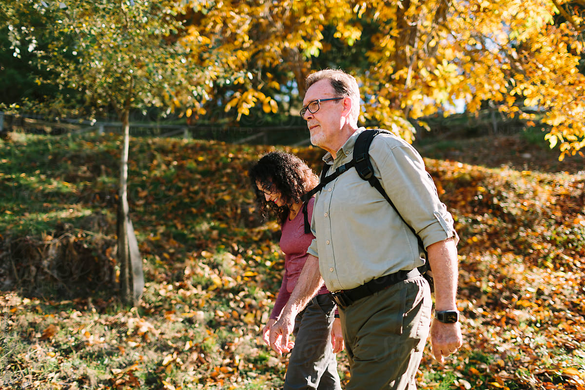 A senior couple trekking in the woods on an Autumn day