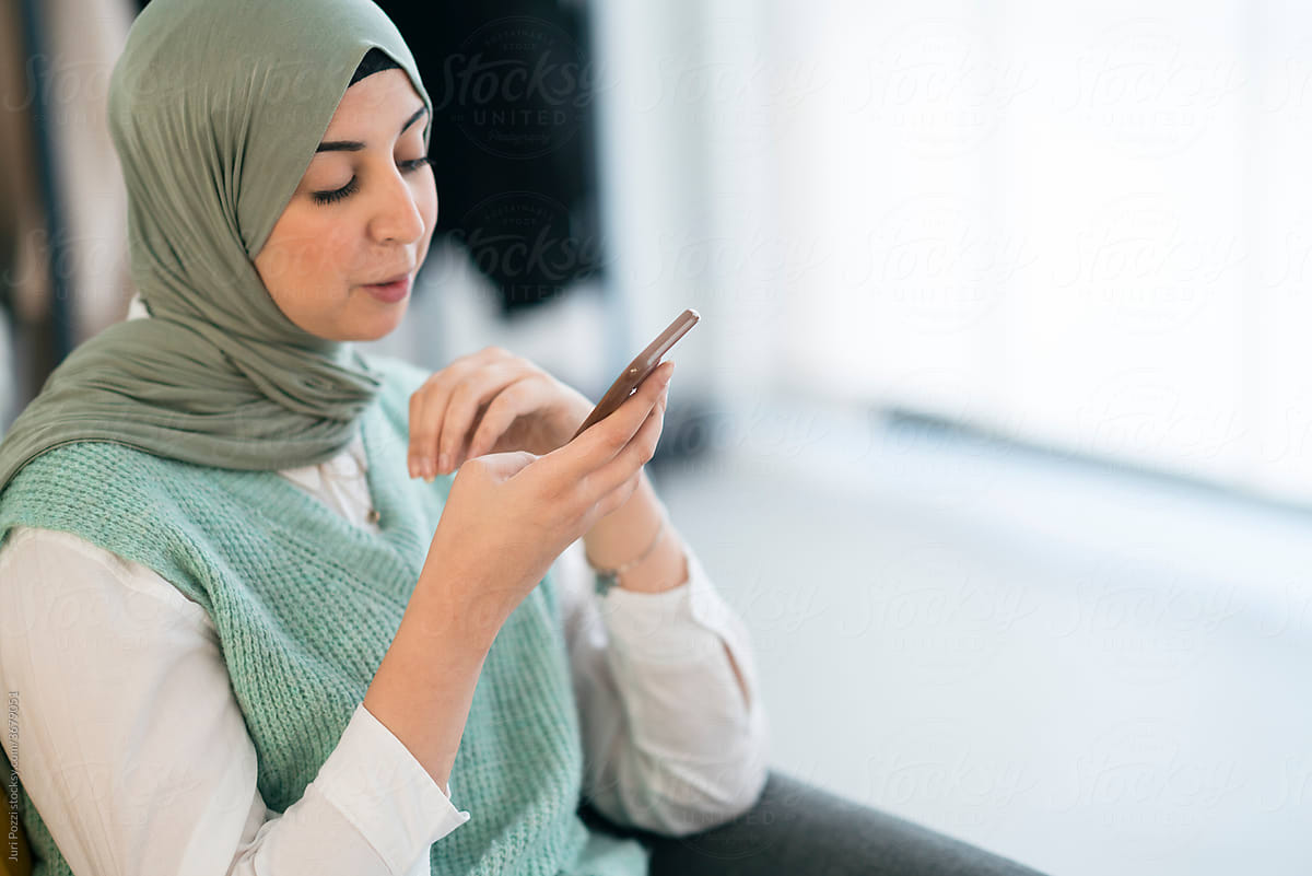 Muslim woman recording voice message on smartphone