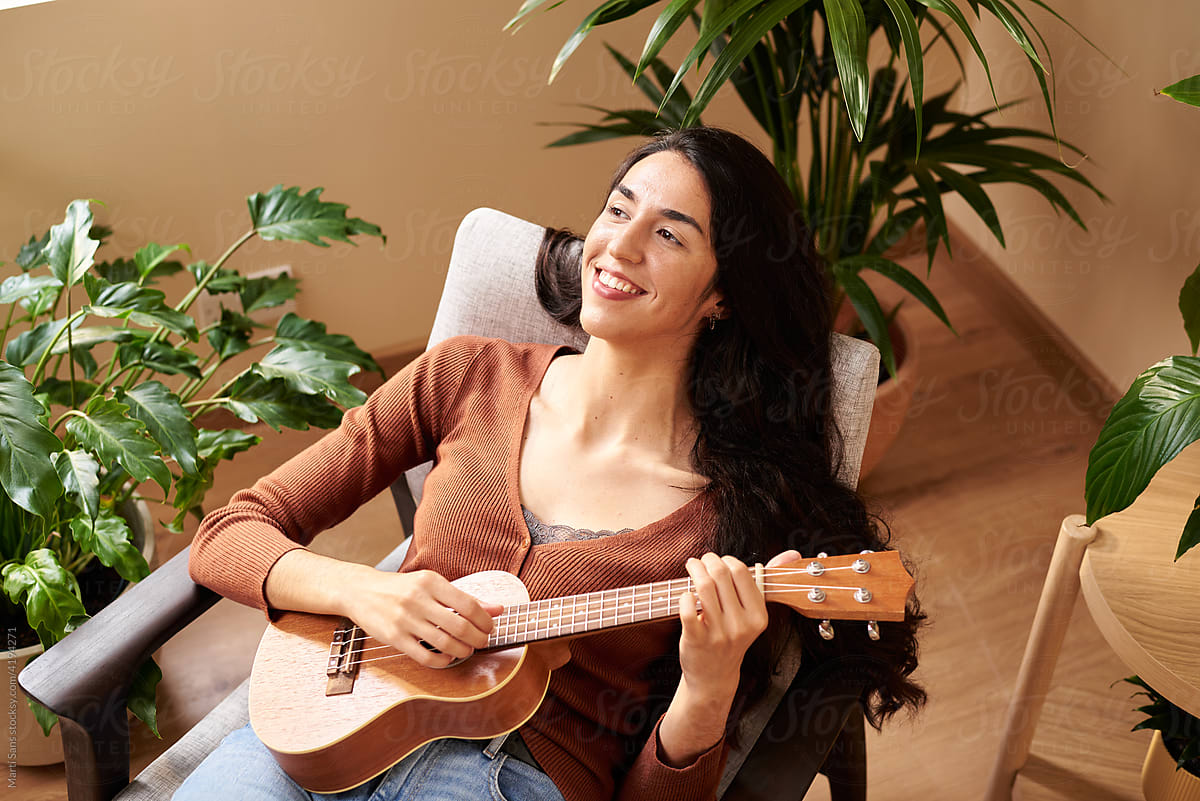 Content musician playing ukulele at home