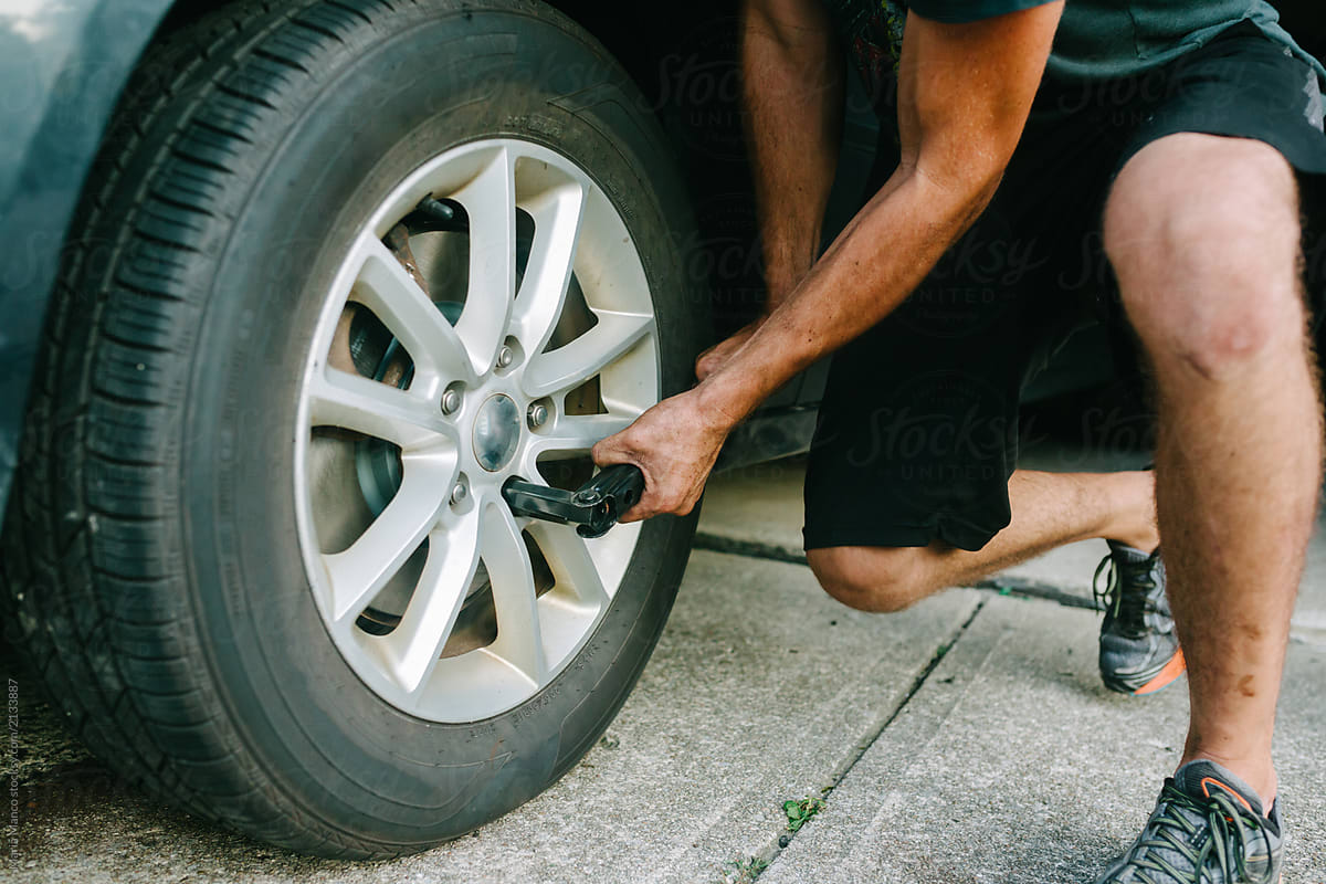 man changes tire on car