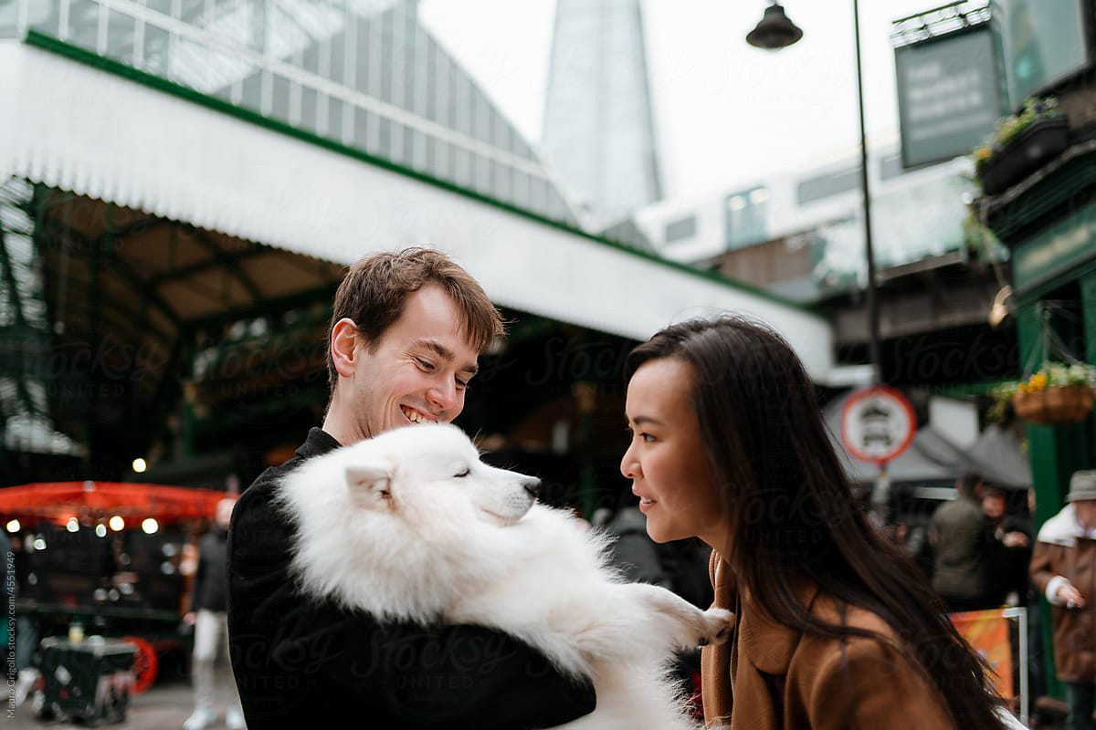 A couple talks to their dog in an urban area