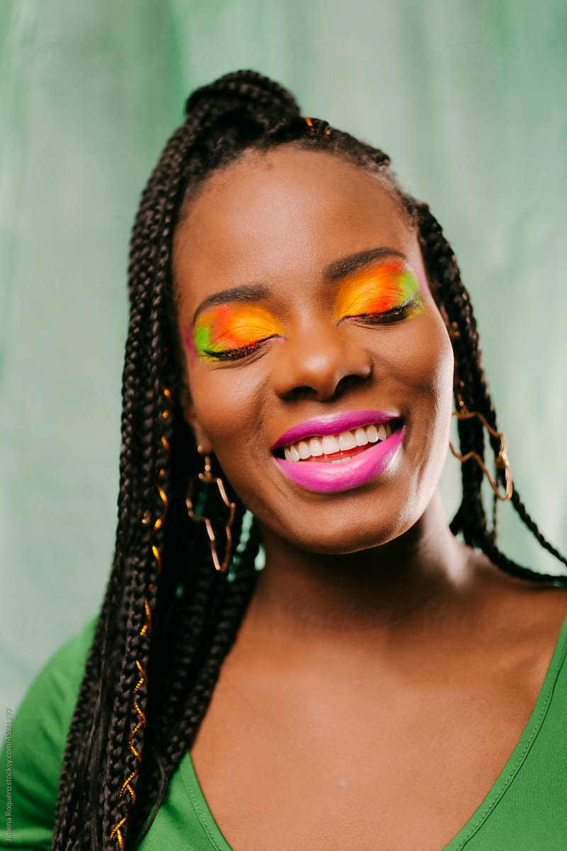 Woman with braided hair and creative colorful  makeup smiling.