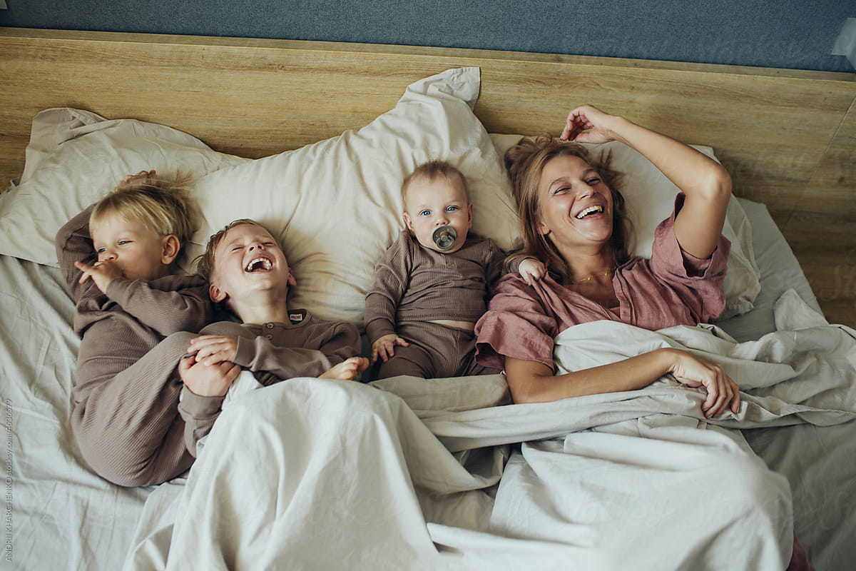 Mom with three little sons woke up in the morning in the bedroom