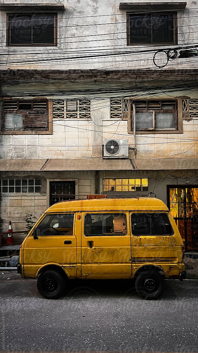 A yellow van parked in an alleyway
