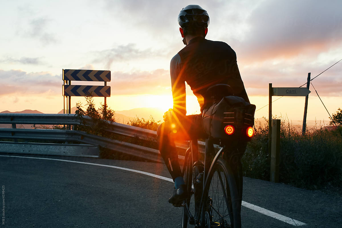 golden hour cyclist watching sunrise on mountain road