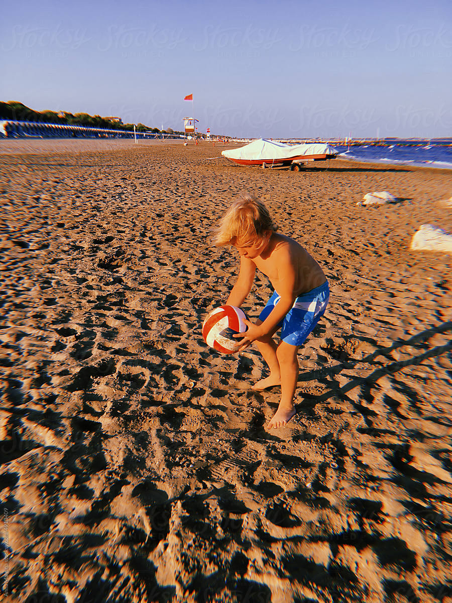a boy with a ball on a beach