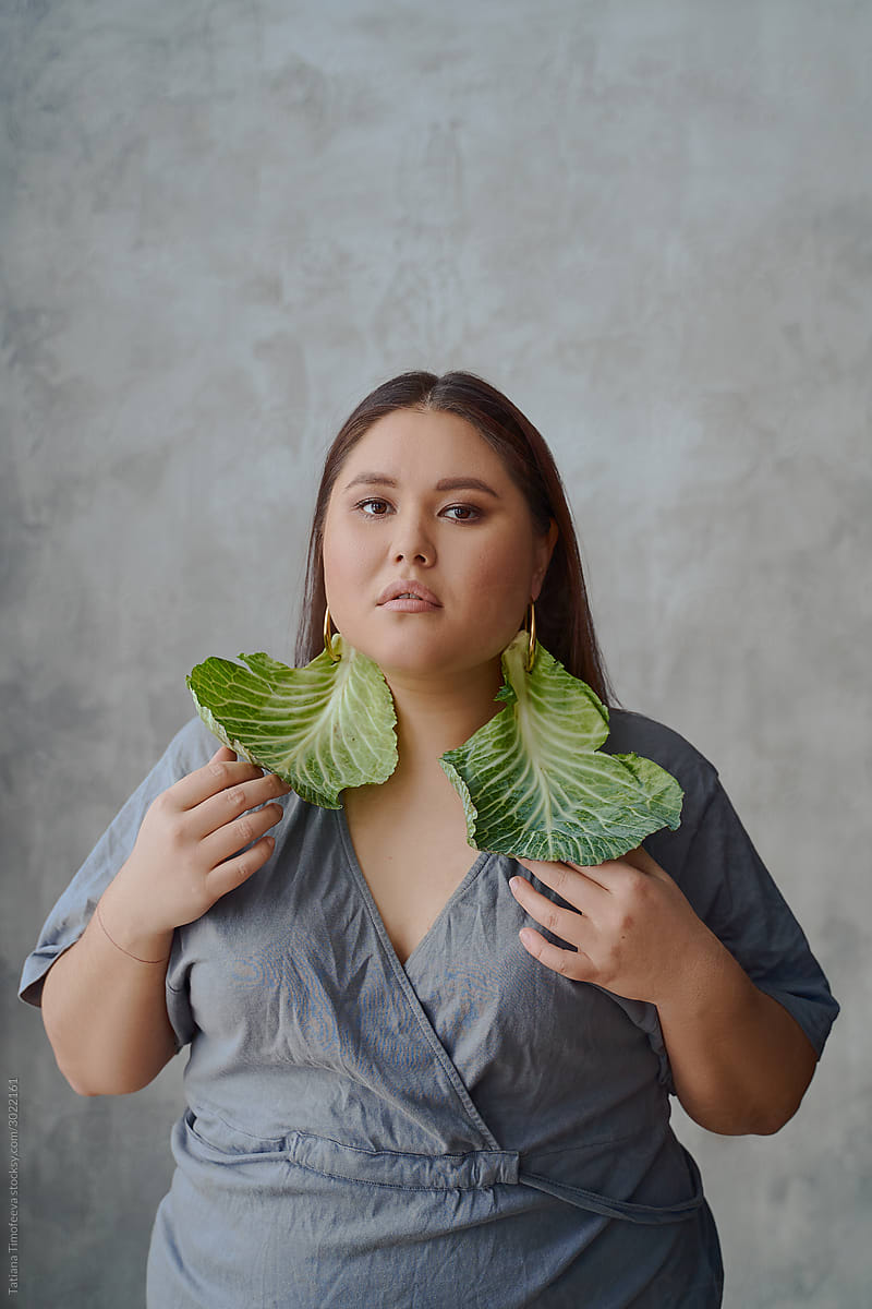 portrait of an Asian woman in a dress cabbage earrings on a gray background