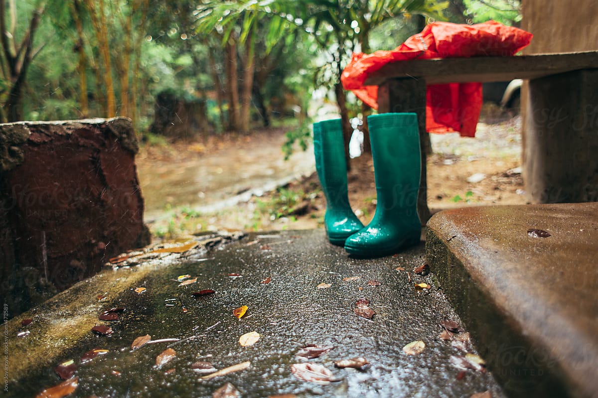 Green gumboots and red rain coat during rainfall