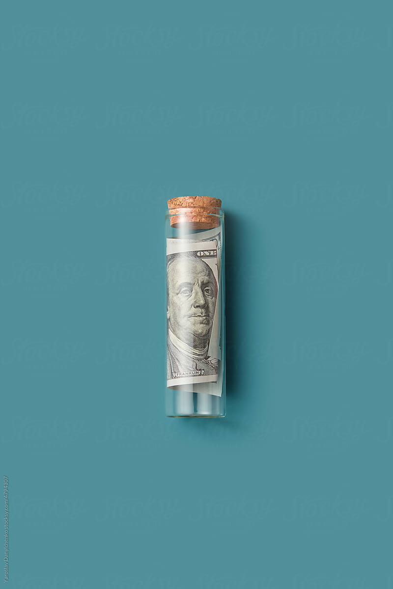 Dollar banknote rolled up in small glass bottle.