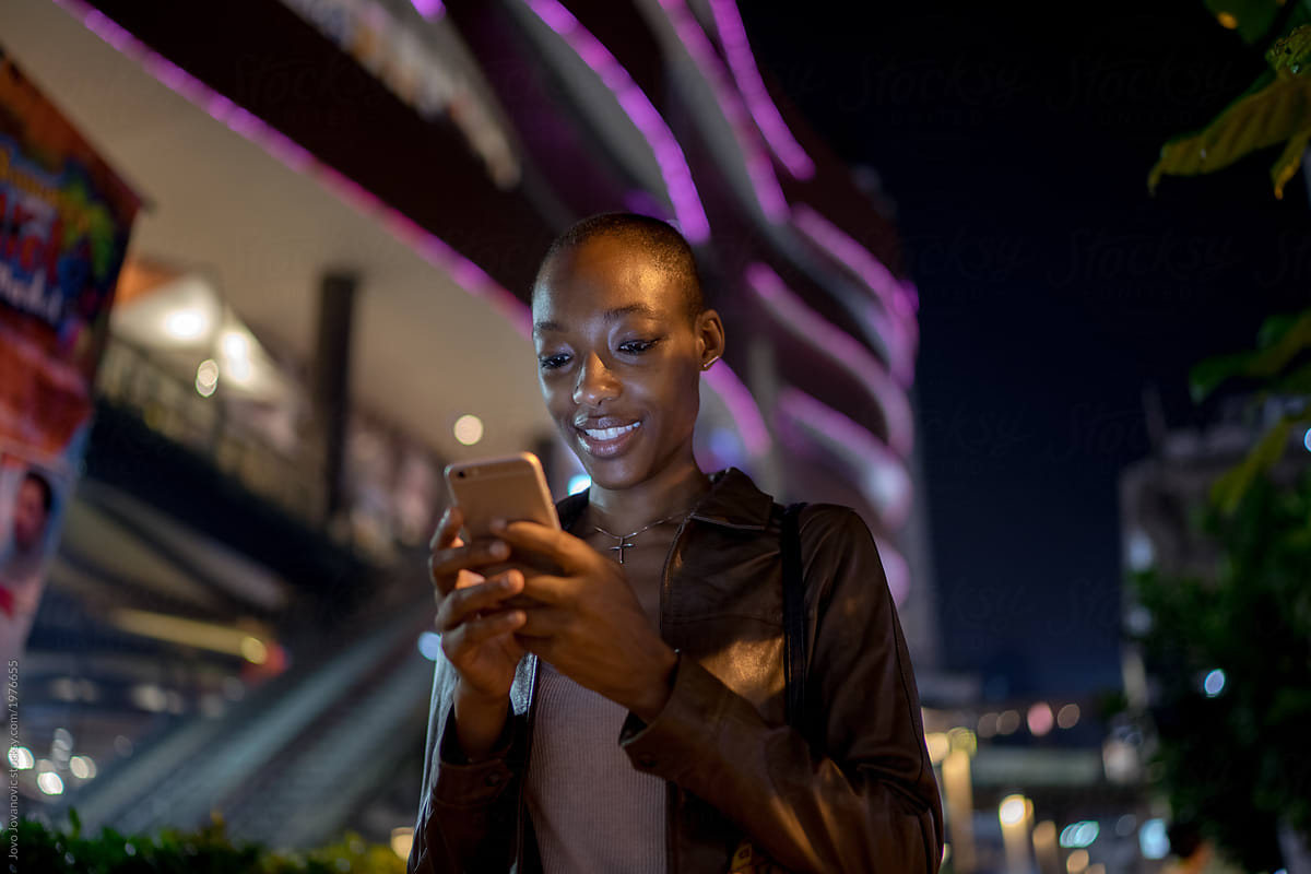 Night portrait of a woman smiling at her phone
