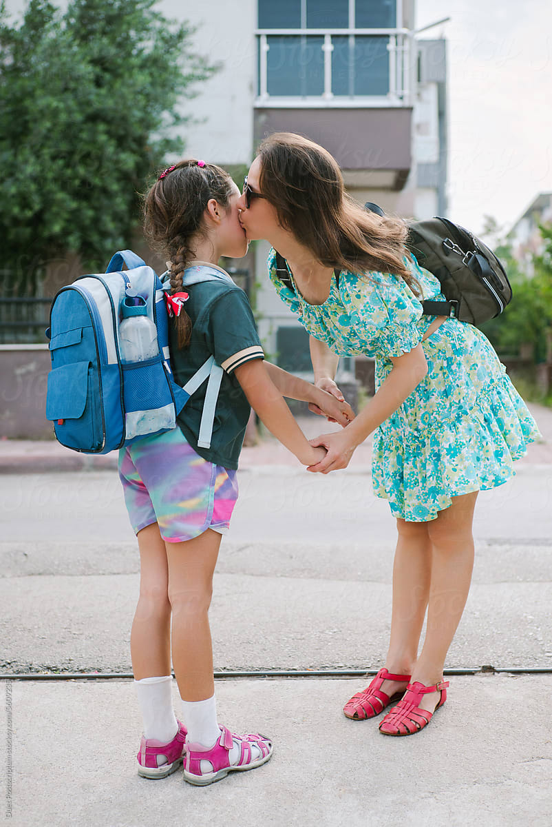 Young mom kisses her daughter before going to school