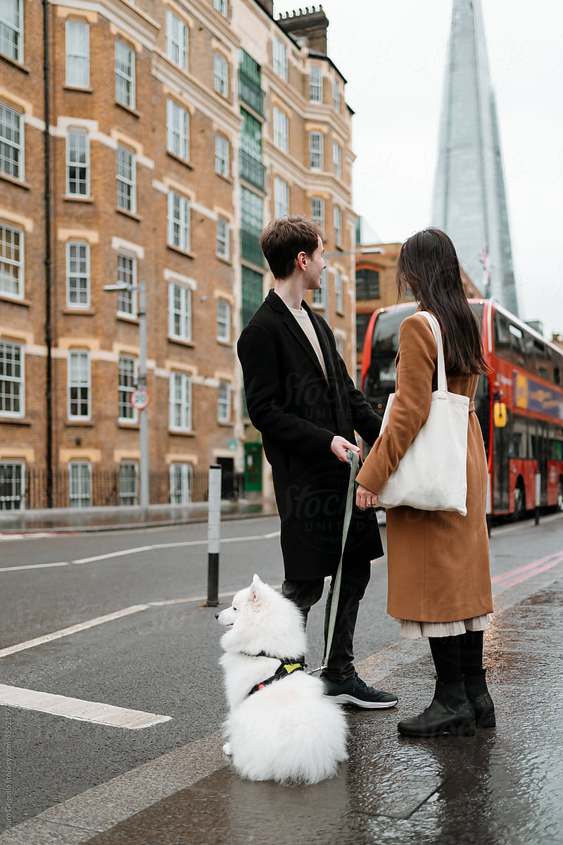 Couple outdoors with their dog and waiting for the bus