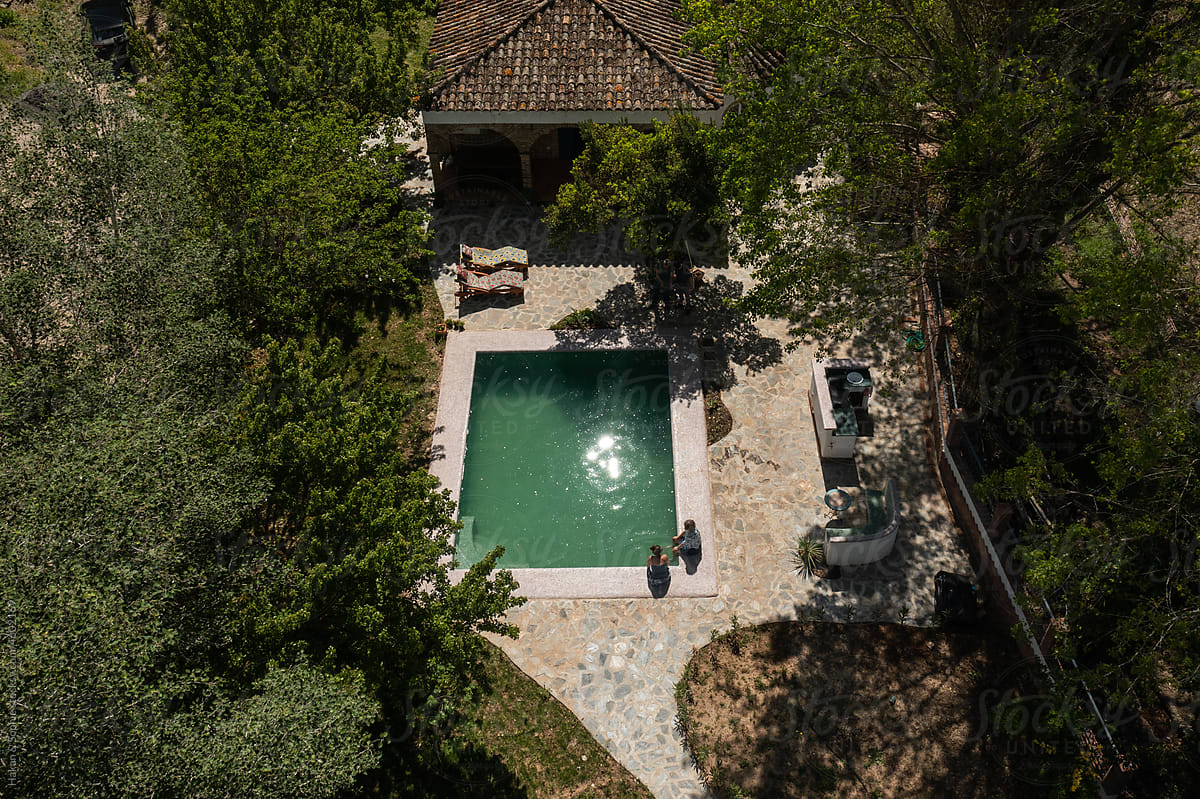 aerial view of people sitting on the edge of a emerald green pool