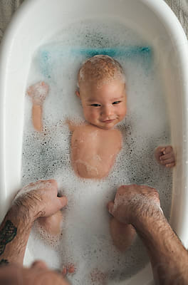 Smiling Caucasian toddler enjoying bubble bath in domestic