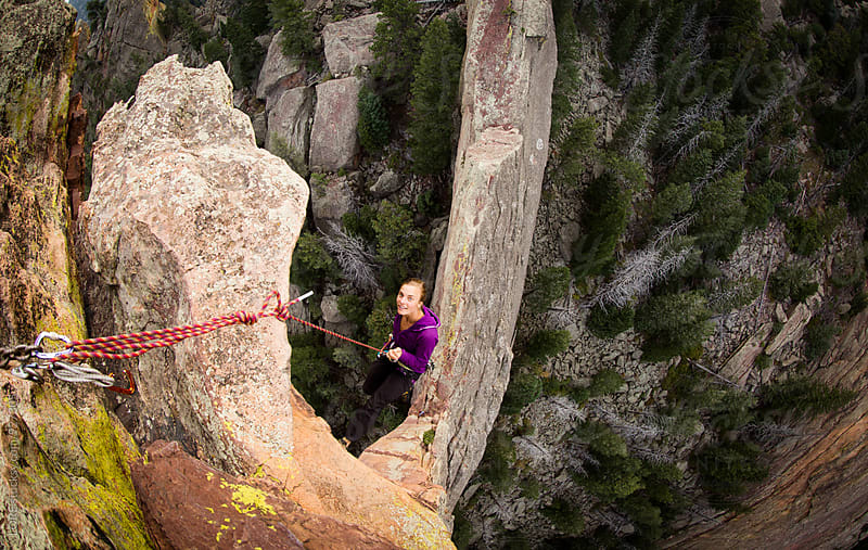 Young Adult Woman Rappels off exposed rock on the Maiden in Colorado