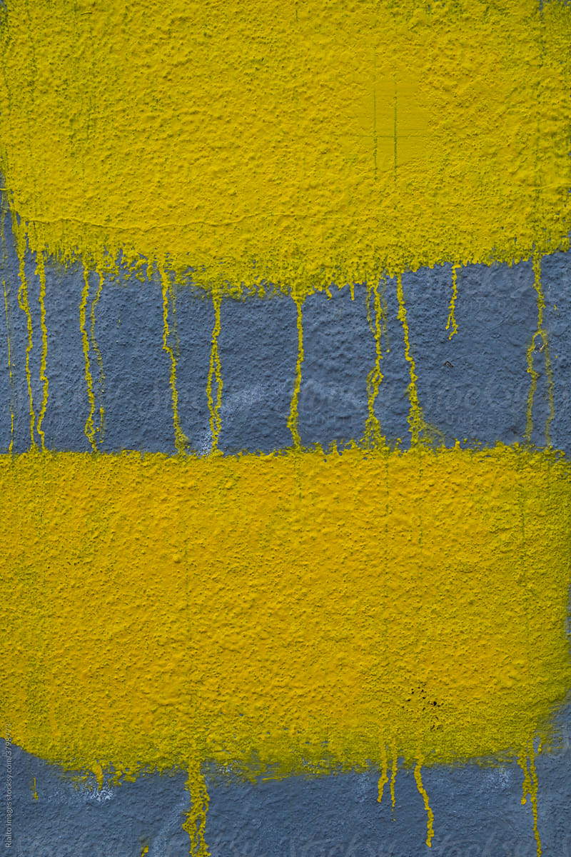 Dripping yellow paint covering graffiti on building wall, close up