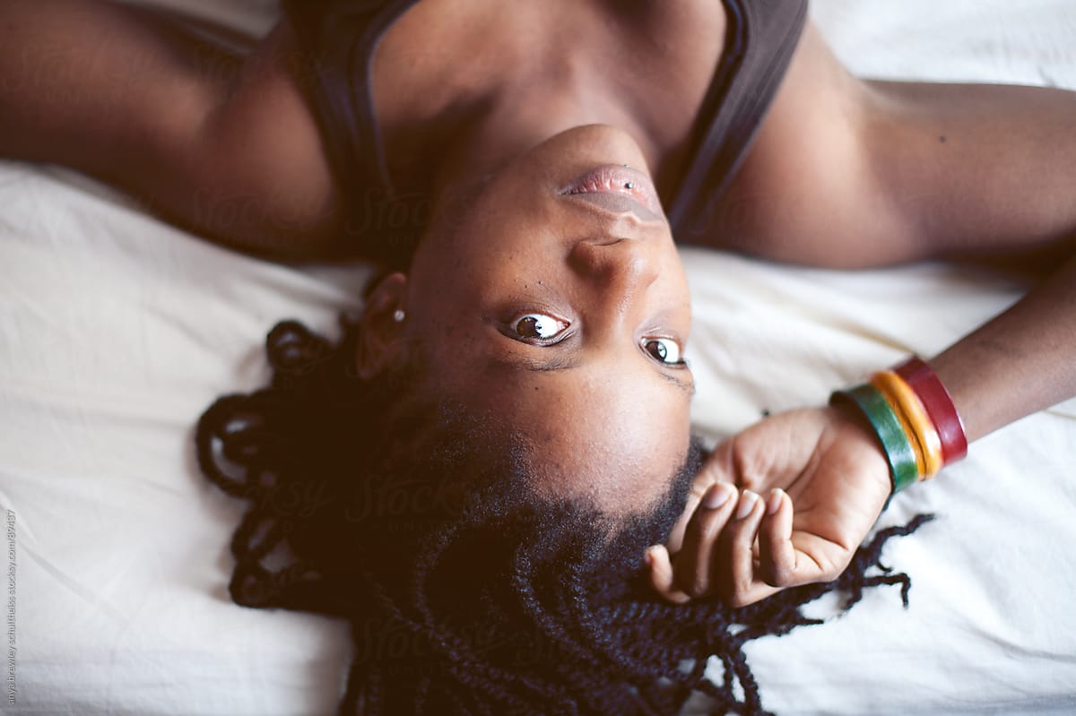 Portrait of black woman lying head down on a bed