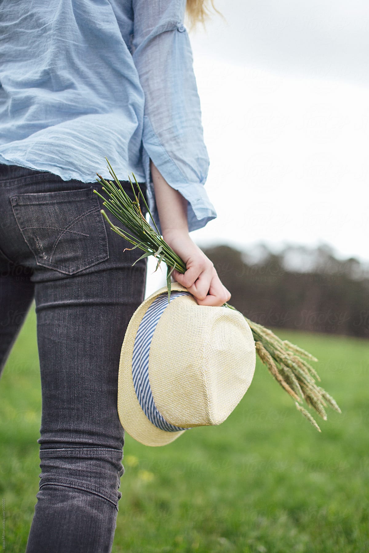 Back View Of Girl In Field Holding Flowers And Hat By Stocksy Contributor Jacqui Miller