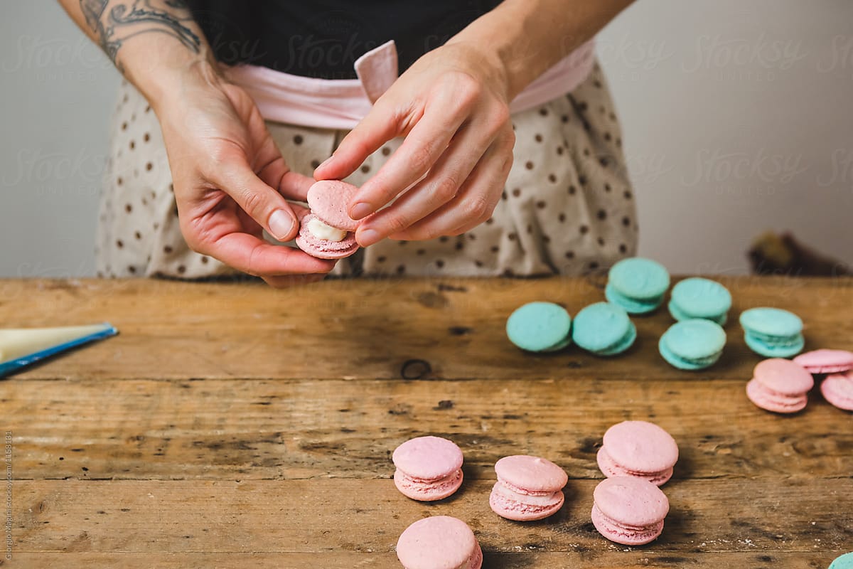 Woman Preparing Colored Macarons on a Wooden Table