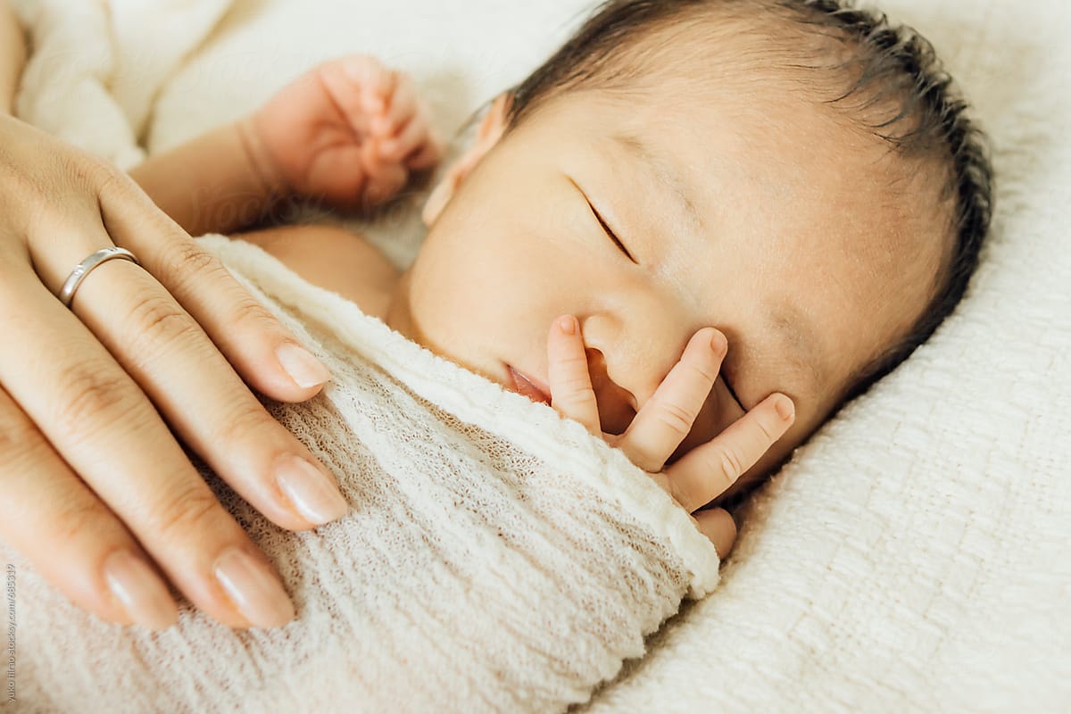 Small fingers of sleeping Asian newborn baby