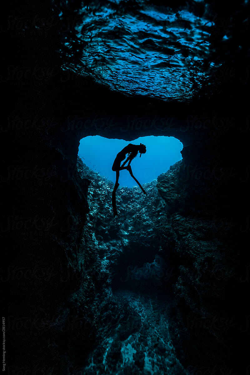 A female free diver diving in the heart shape cave