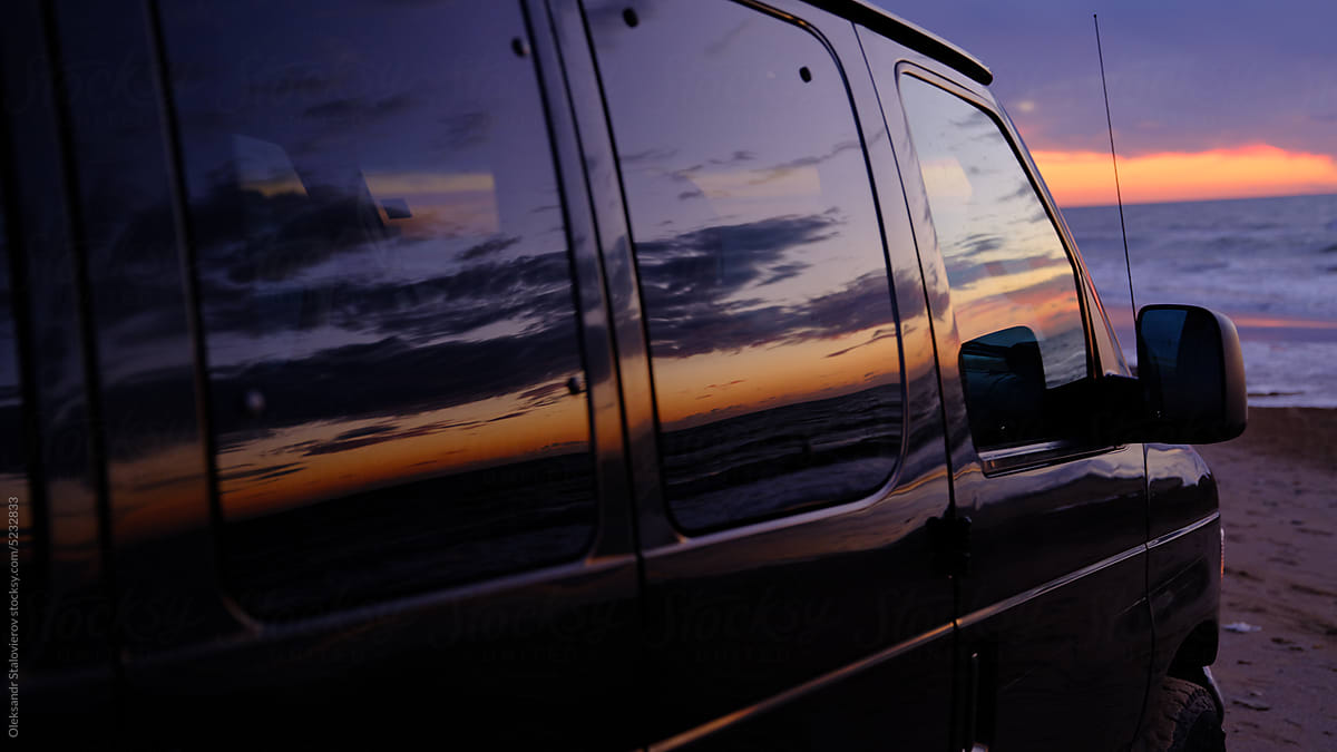 Reflection  Sunrise in car doors on beach near fireplace on the  sea.