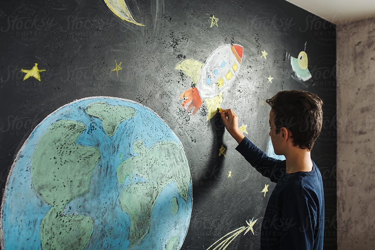 Boy decorating his wall with drawing of planets and rocket