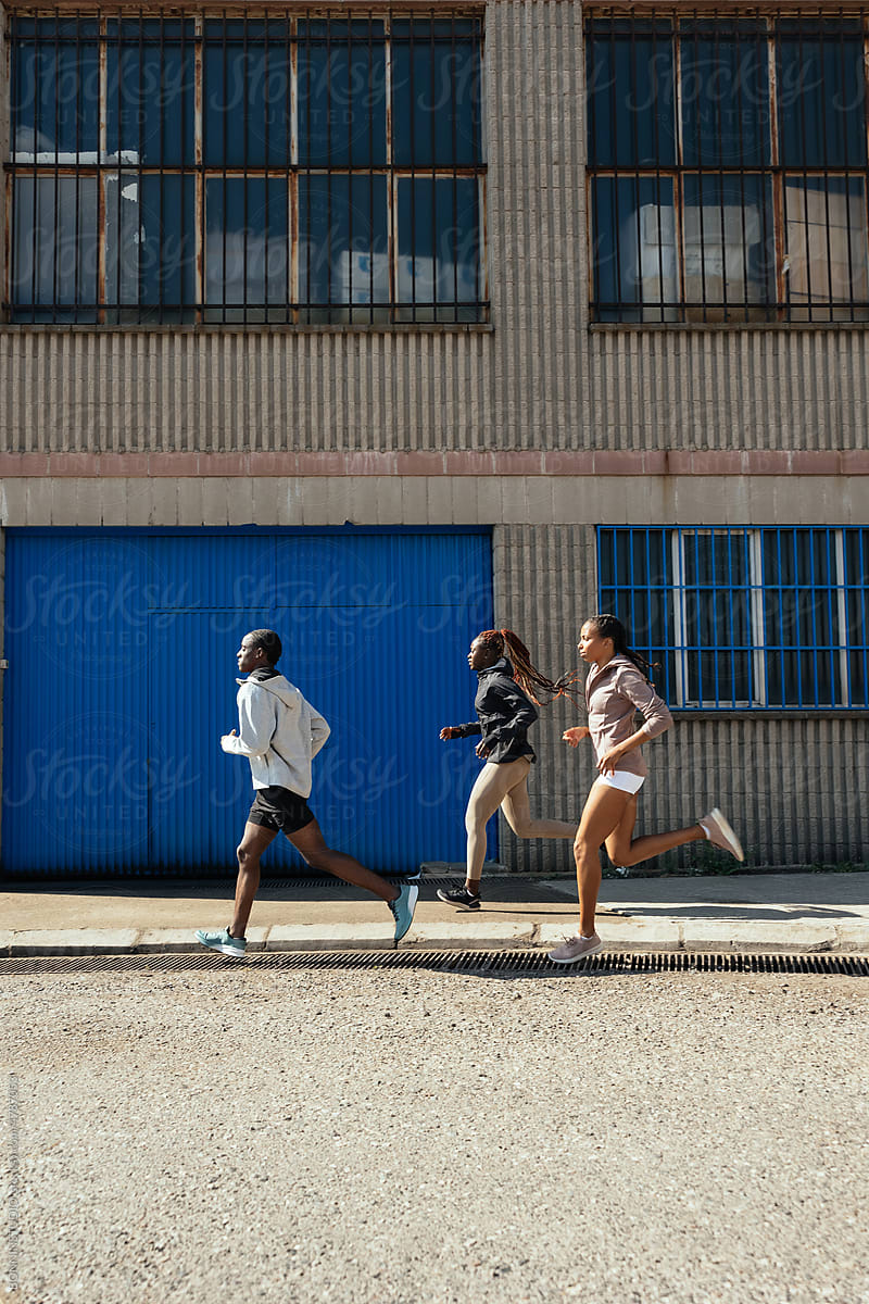 Sportspeople running outside industrial building
