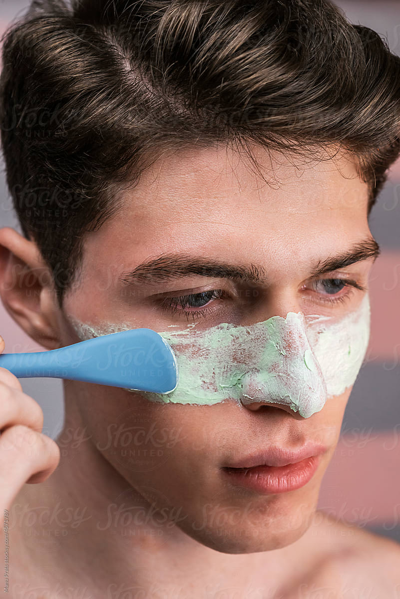 Modern man applying facial mask, male skincare