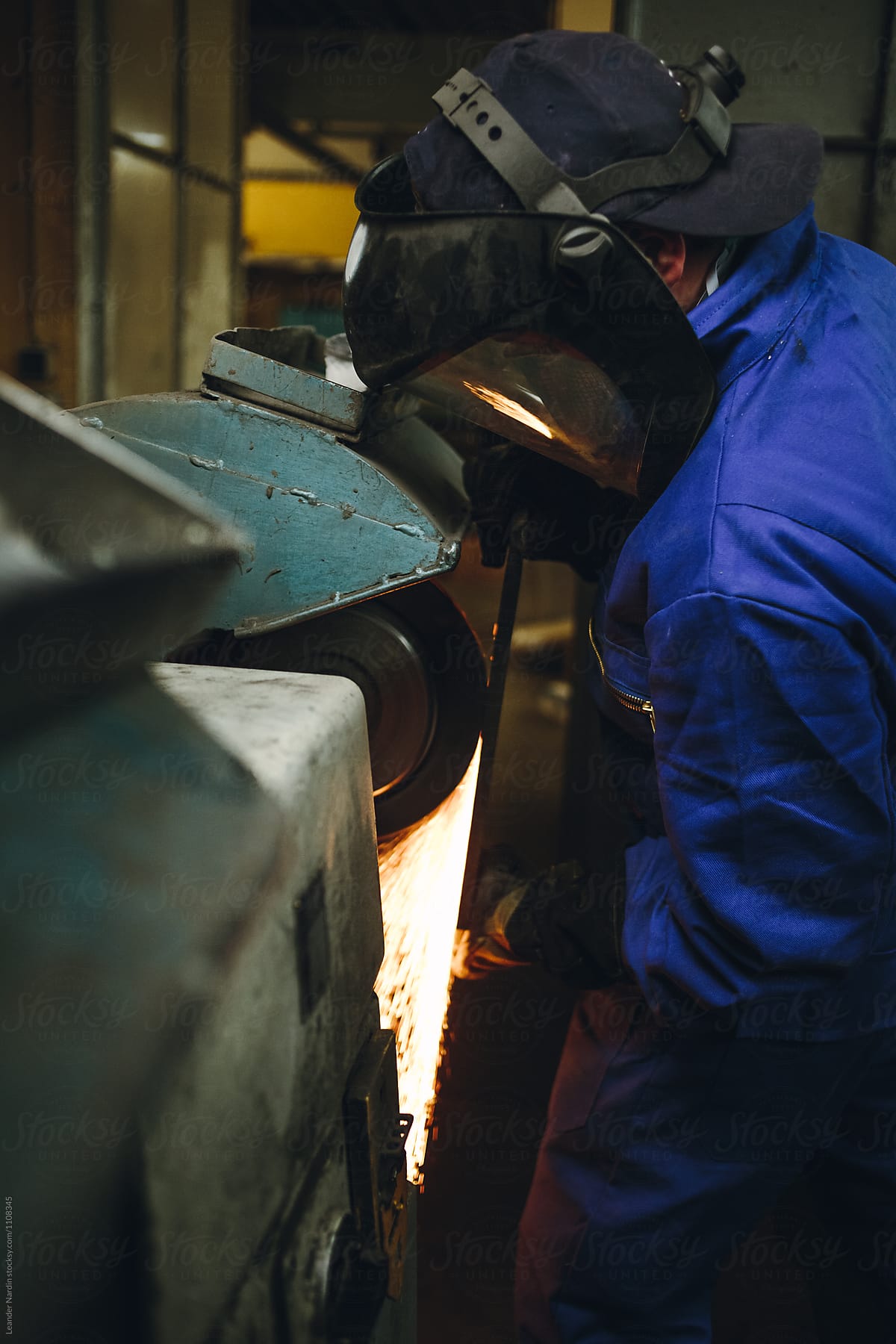 detail of a metal worker with protection mask grinding metal plate in a workshop