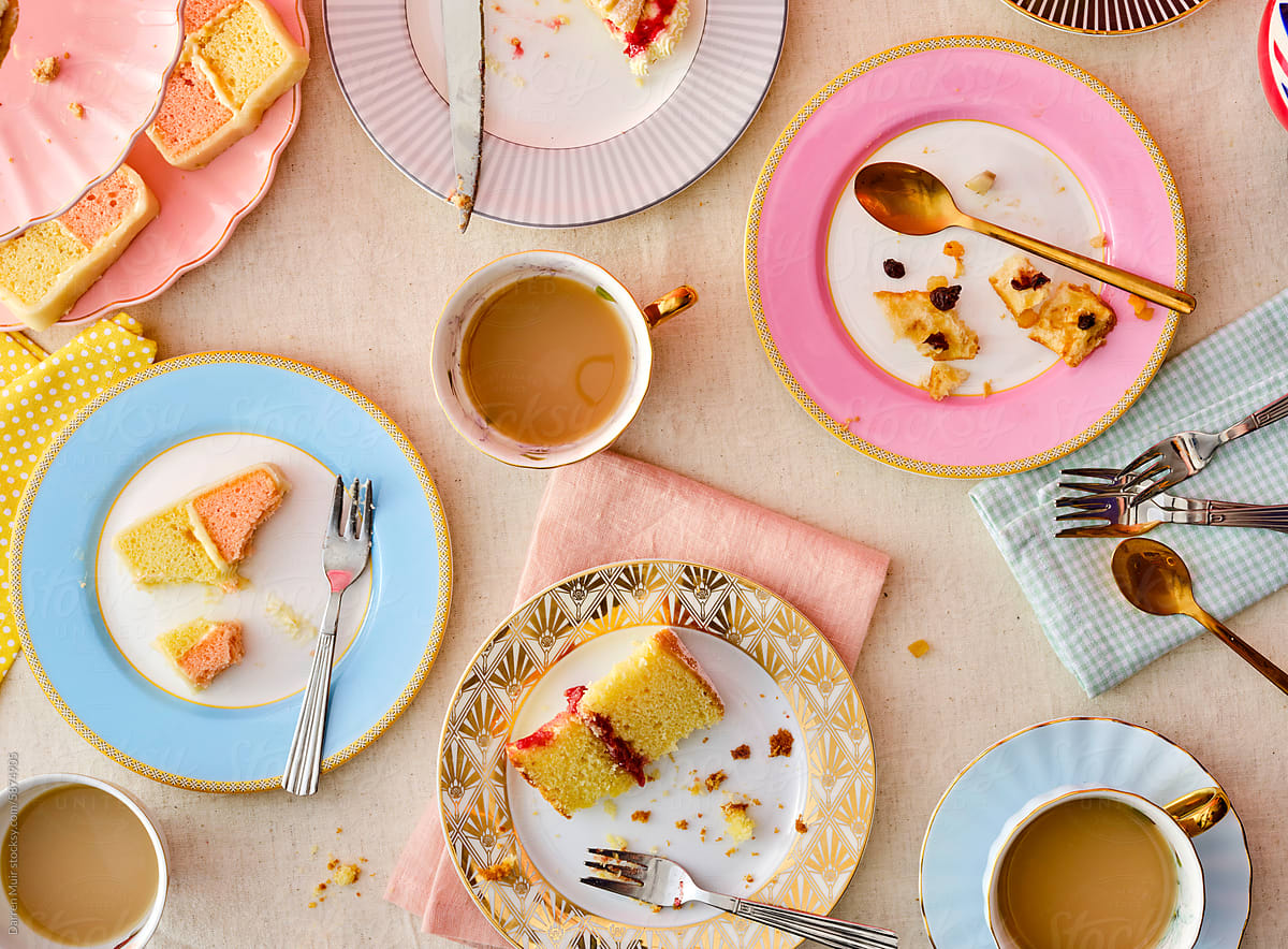 Messy table with leftover cake and cups of tea.
