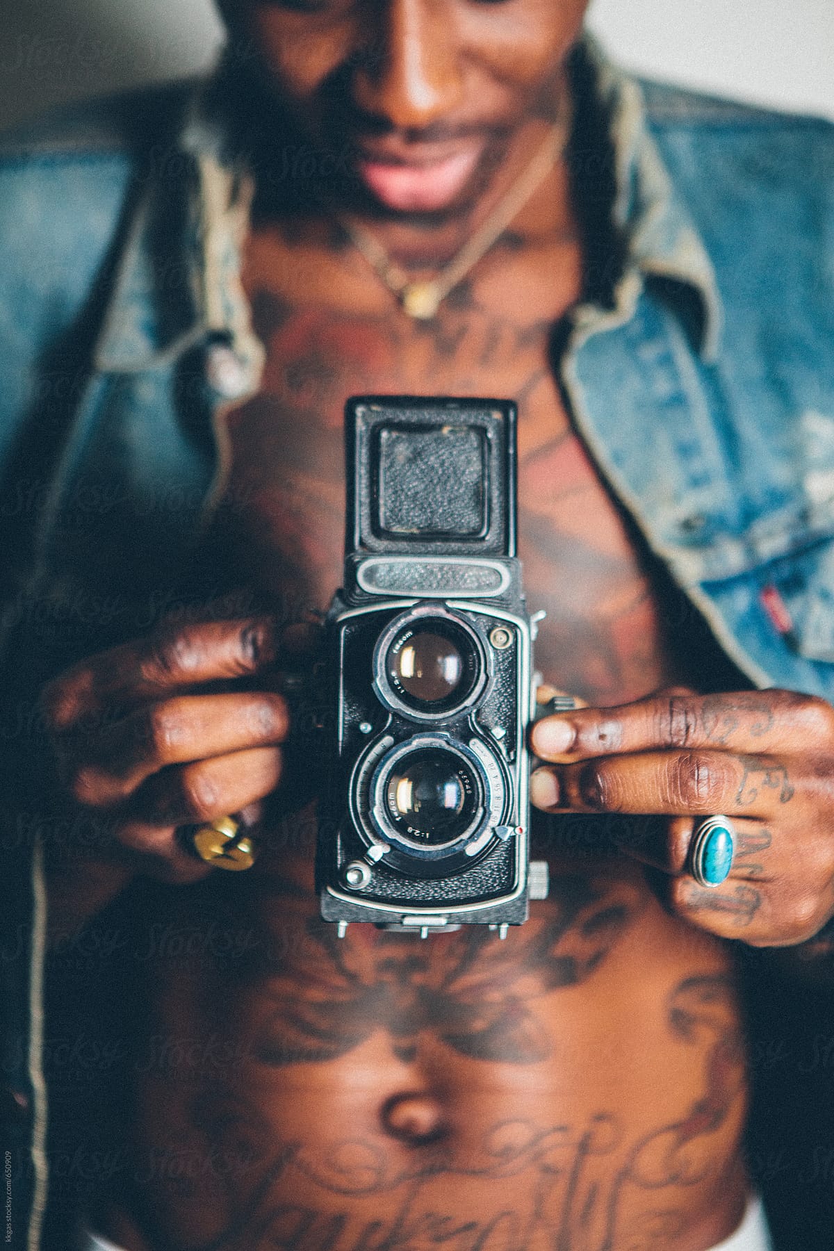Close up of young tattooed black man using a vintage camera